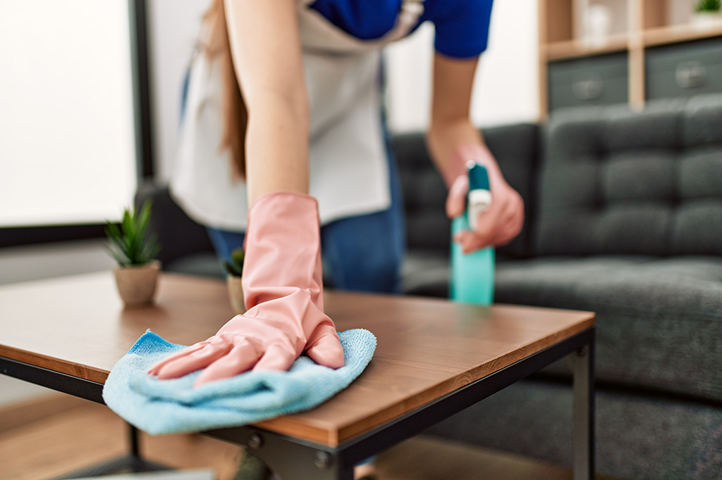 A cleaning employee wiping down a coffee table